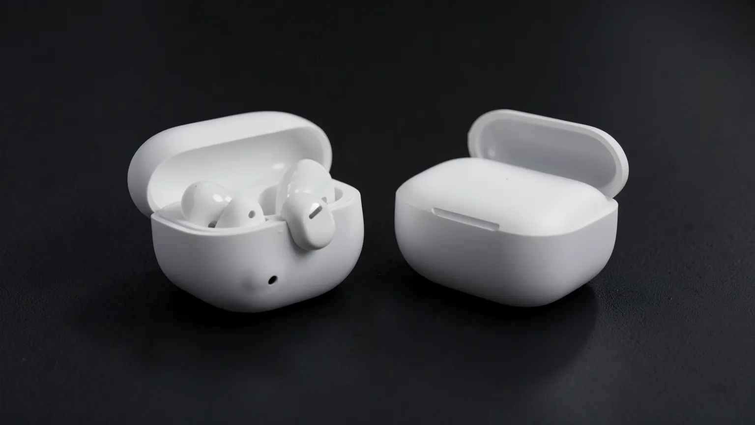 Auriculares inalámbricos blancos junto a su estuche abierto sobre una mesa oscura