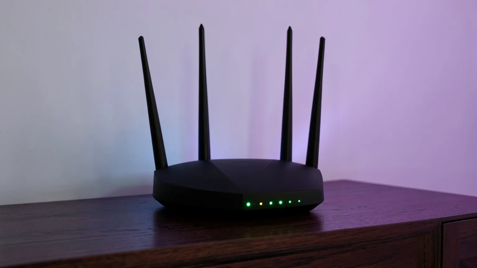 Router inalámbrico negro con antenas desplegadas sobre un mueble, iluminado por luces verdes y violetas