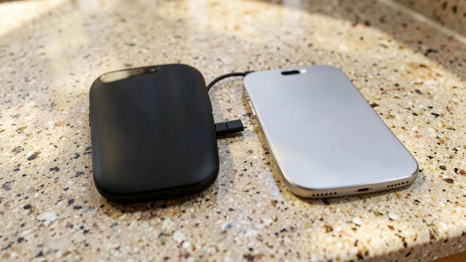 Dos teléfonos de marcas distintas conectados entre sí por un cable sobre una mesa de cocina